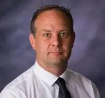 Professional headshot of a man in a white shirt and black tie.